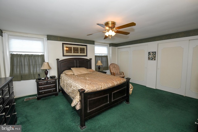 bedroom featuring dark colored carpet, multiple windows, and ceiling fan