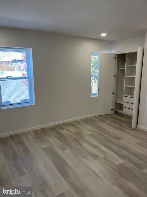 unfurnished bedroom featuring multiple windows, a closet, and hardwood / wood-style flooring