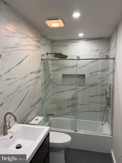 full bathroom with vanity, enclosed tub / shower combo, and toilet