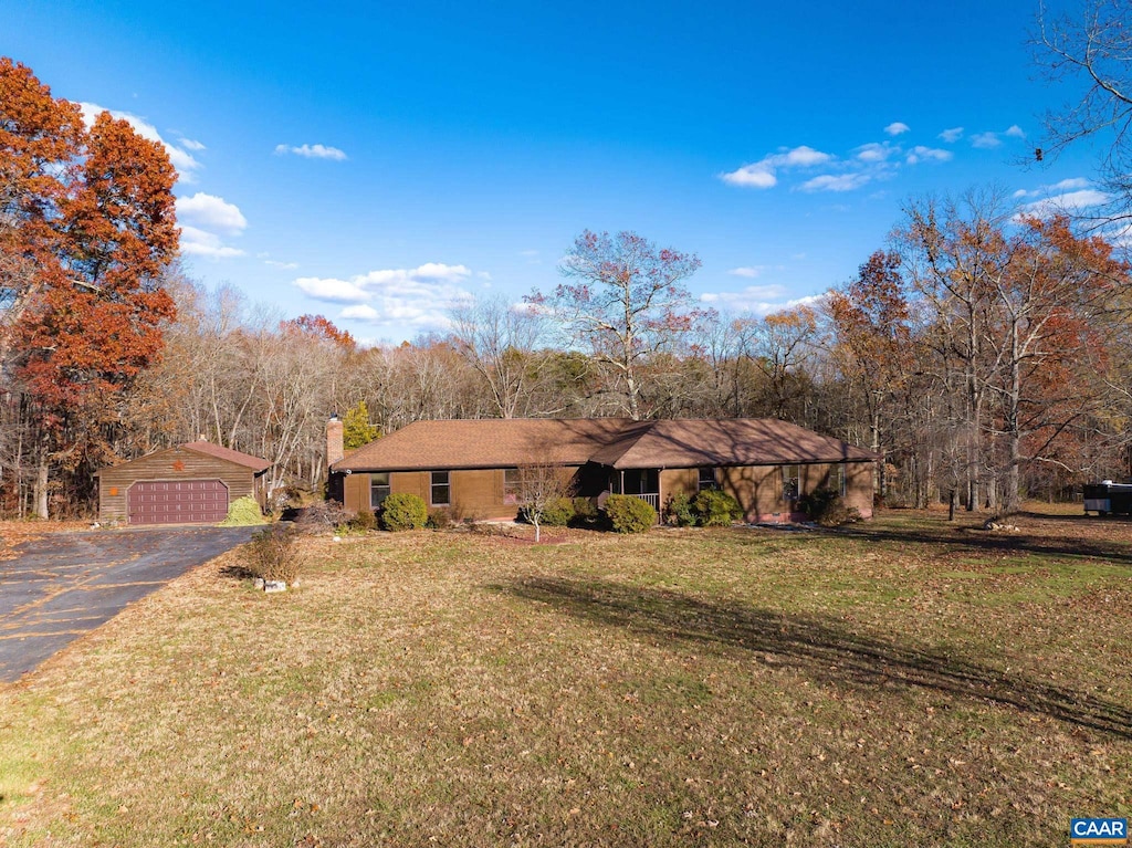 single story home featuring an outbuilding and a front lawn