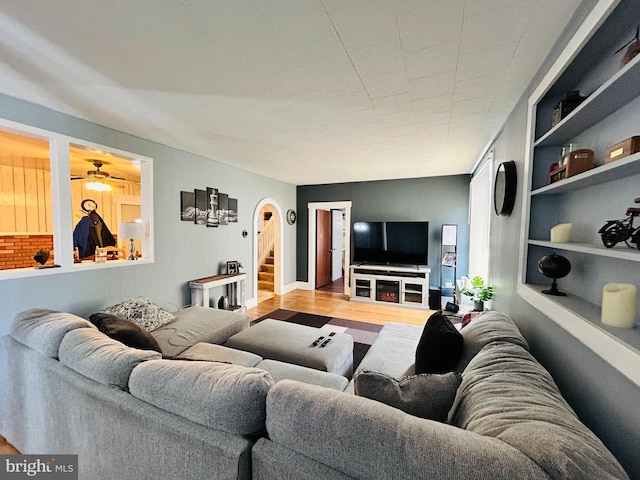 living room with ceiling fan, built in features, and light wood-type flooring