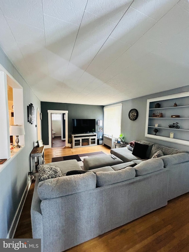 living room featuring hardwood / wood-style floors, a textured ceiling, and built in features