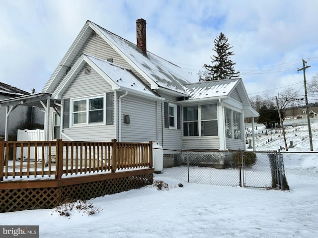 snow covered property with a sunroom and a wooden deck