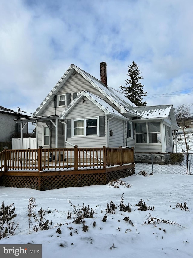 snow covered rear of property with a wooden deck