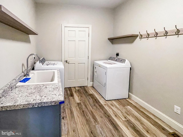 washroom with independent washer and dryer, dark hardwood / wood-style floors, and sink