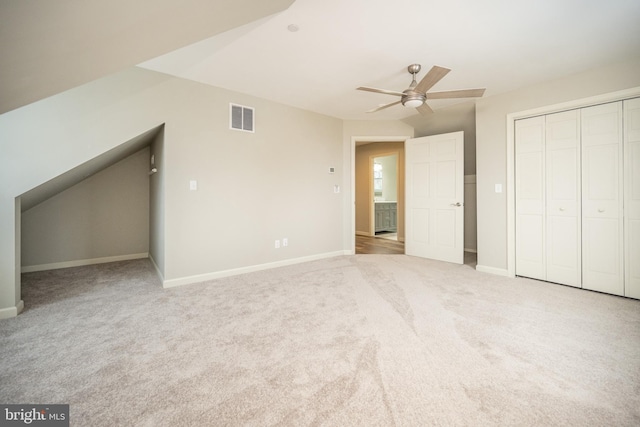 unfurnished bedroom featuring light carpet, a closet, and ceiling fan