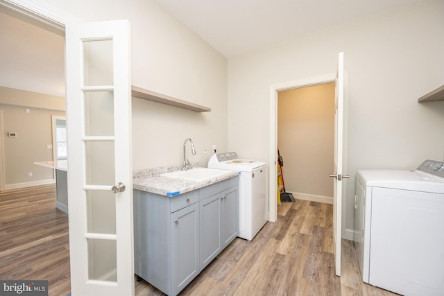 clothes washing area featuring light hardwood / wood-style floors, cabinets, independent washer and dryer, and sink