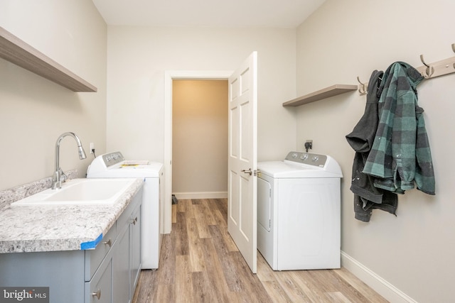 washroom featuring cabinets, independent washer and dryer, light hardwood / wood-style flooring, and sink