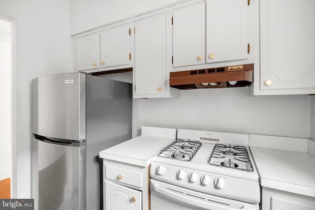 kitchen with stainless steel refrigerator, white cabinetry, premium range hood, and white range with gas cooktop