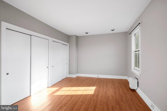 unfurnished bedroom with two closets and hardwood / wood-style flooring