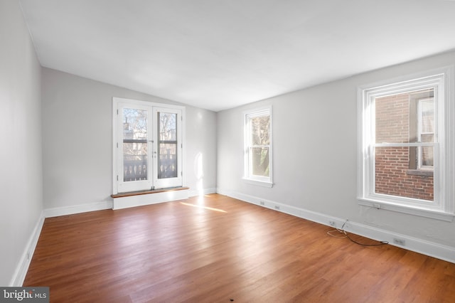 unfurnished room featuring hardwood / wood-style flooring and lofted ceiling