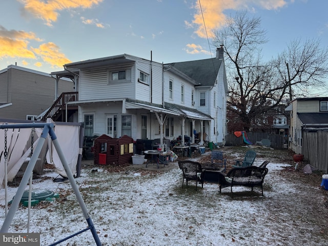 snow covered rear of property with an outdoor fire pit