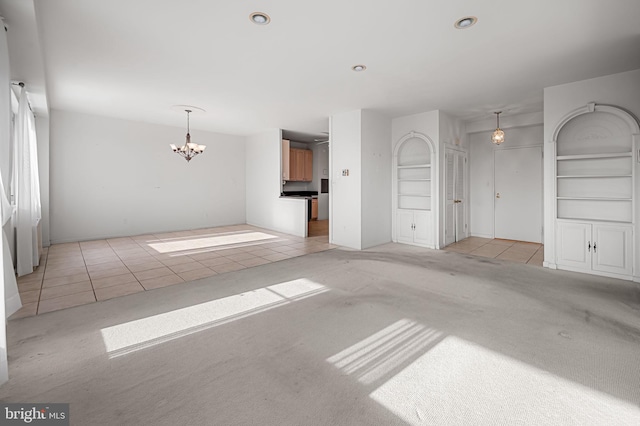 unfurnished living room featuring an inviting chandelier, light carpet, and built in features