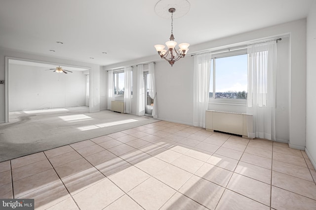 empty room featuring ceiling fan with notable chandelier, light tile patterned flooring, and a healthy amount of sunlight