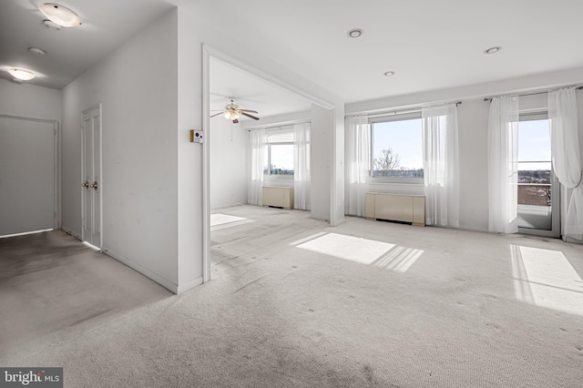 unfurnished living room featuring ceiling fan and light colored carpet