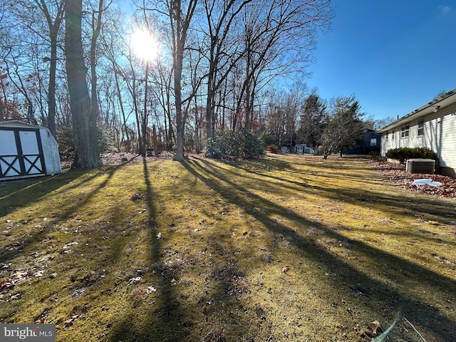 view of yard with central AC and a storage shed