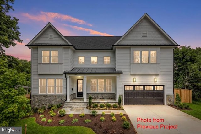 view of front of property with fence, a standing seam roof, concrete driveway, a garage, and stone siding