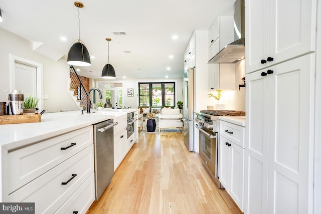 kitchen featuring white cabinetry, high quality appliances, and wall chimney range hood