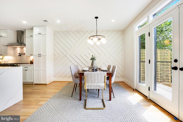 dining space featuring an inviting chandelier, light hardwood / wood-style flooring, and wood walls