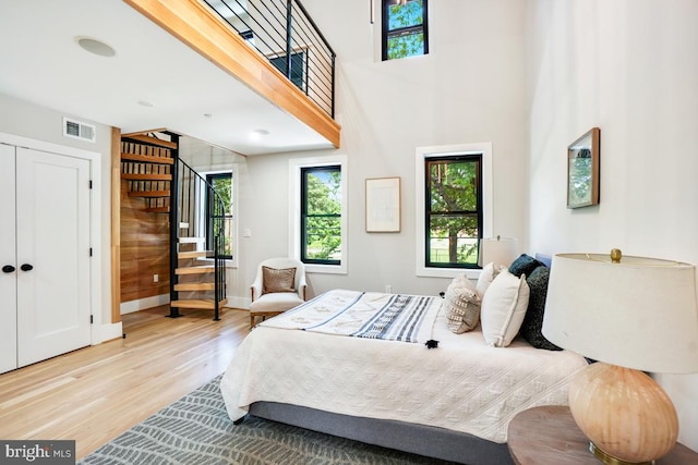 bedroom featuring a high ceiling, light hardwood / wood-style floors, and a closet