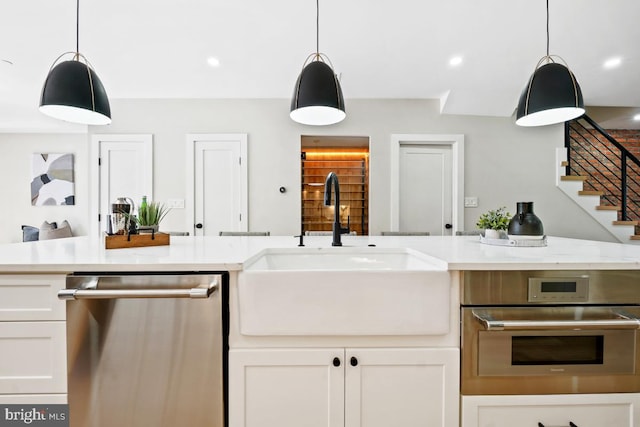 kitchen featuring white cabinetry, sink, pendant lighting, and appliances with stainless steel finishes