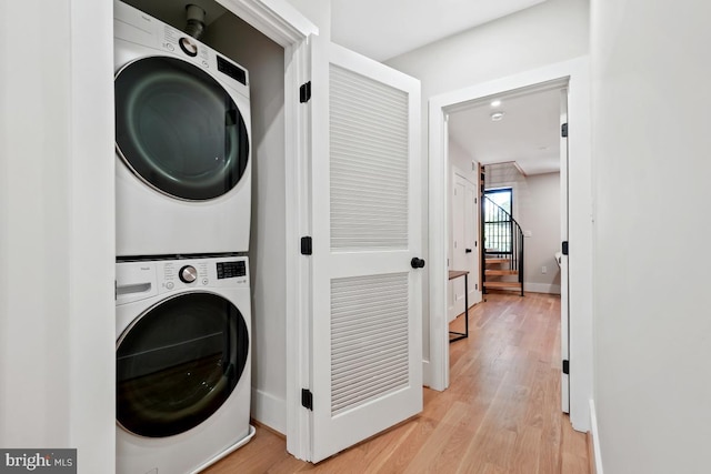 clothes washing area featuring stacked washer / drying machine and light wood-type flooring