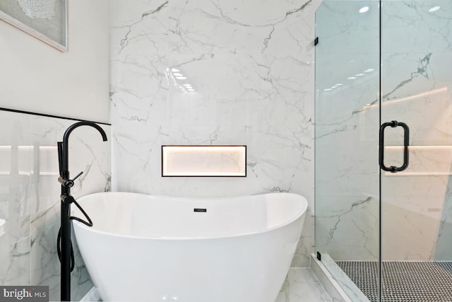 bathroom featuring plus walk in shower and tile walls