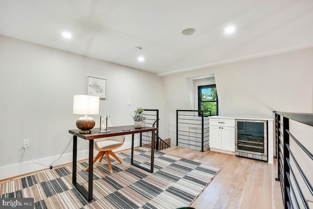 home office with light wood-type flooring and beverage cooler