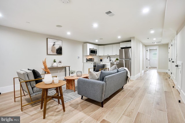 living room with light hardwood / wood-style flooring and sink