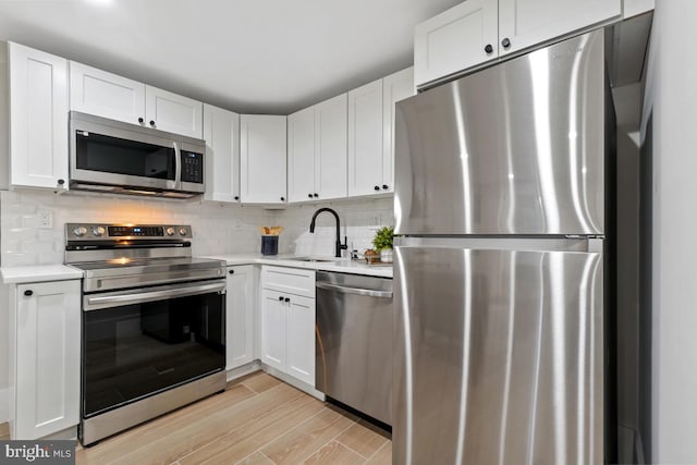 kitchen featuring light wood-type flooring, white cabinetry, sink, and appliances with stainless steel finishes