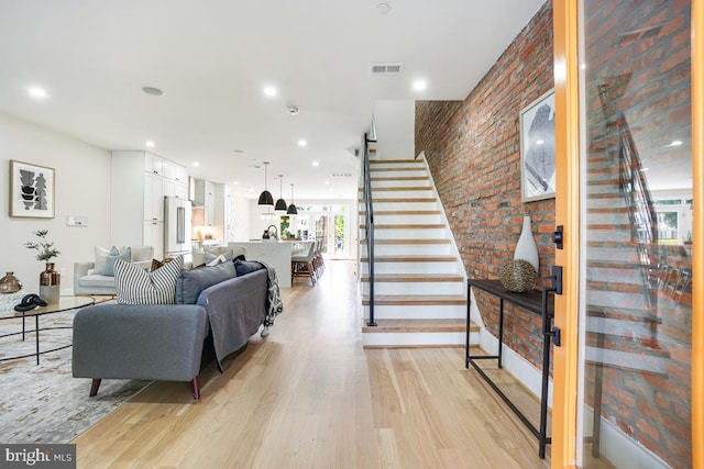 living room featuring brick wall and light hardwood / wood-style flooring