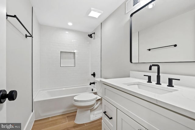 full bathroom with hardwood / wood-style floors, vanity, toilet, and tiled shower / bath