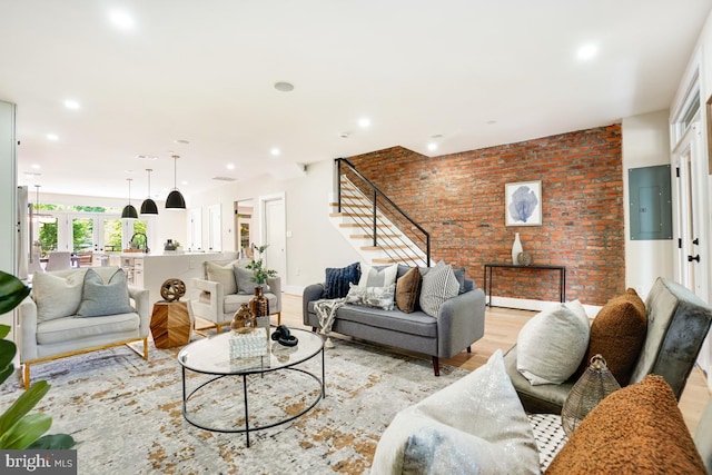 living room with light hardwood / wood-style floors, brick wall, and electric panel