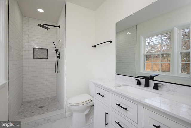 bathroom with tiled shower, vanity, and toilet