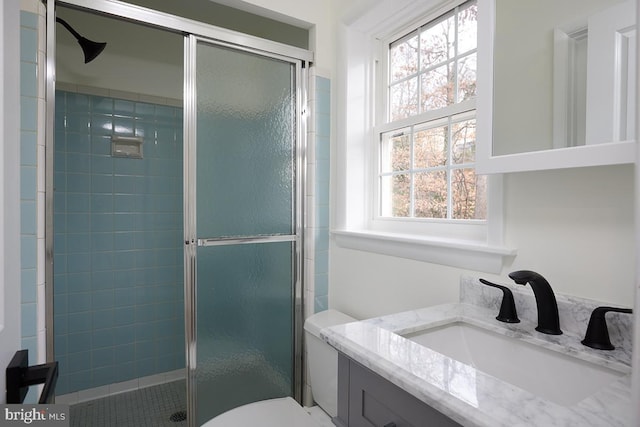 bathroom with vanity, toilet, walk in shower, and a wealth of natural light