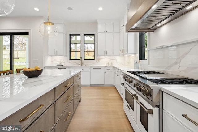 kitchen with wall chimney exhaust hood, white cabinetry, and double oven range