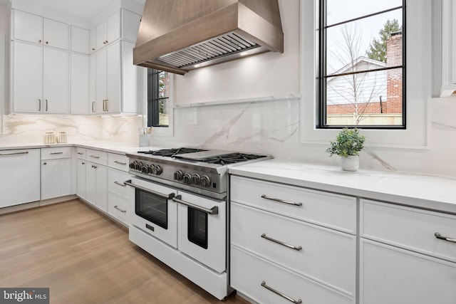 kitchen with light countertops, double oven range, premium range hood, and white cabinetry