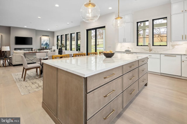 kitchen featuring light stone counters, a kitchen island, decorative light fixtures, and white cabinets