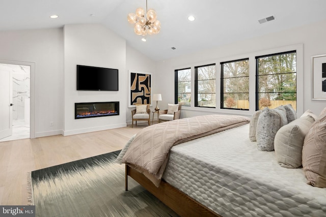 bedroom featuring visible vents, a glass covered fireplace, wood finished floors, an inviting chandelier, and recessed lighting