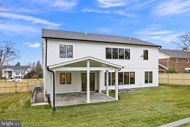 rear view of property featuring a fenced backyard, a patio, and a lawn