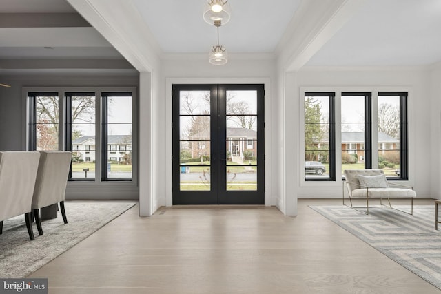 doorway with light wood-style flooring, crown molding, and french doors