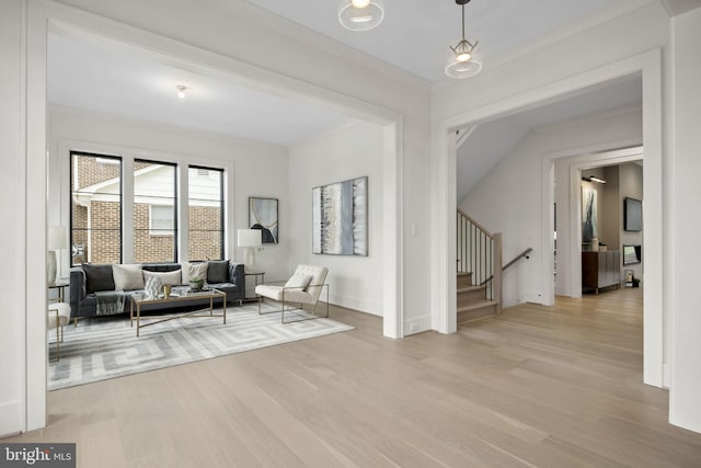 interior space with stairs, light wood finished floors, baseboards, and crown molding