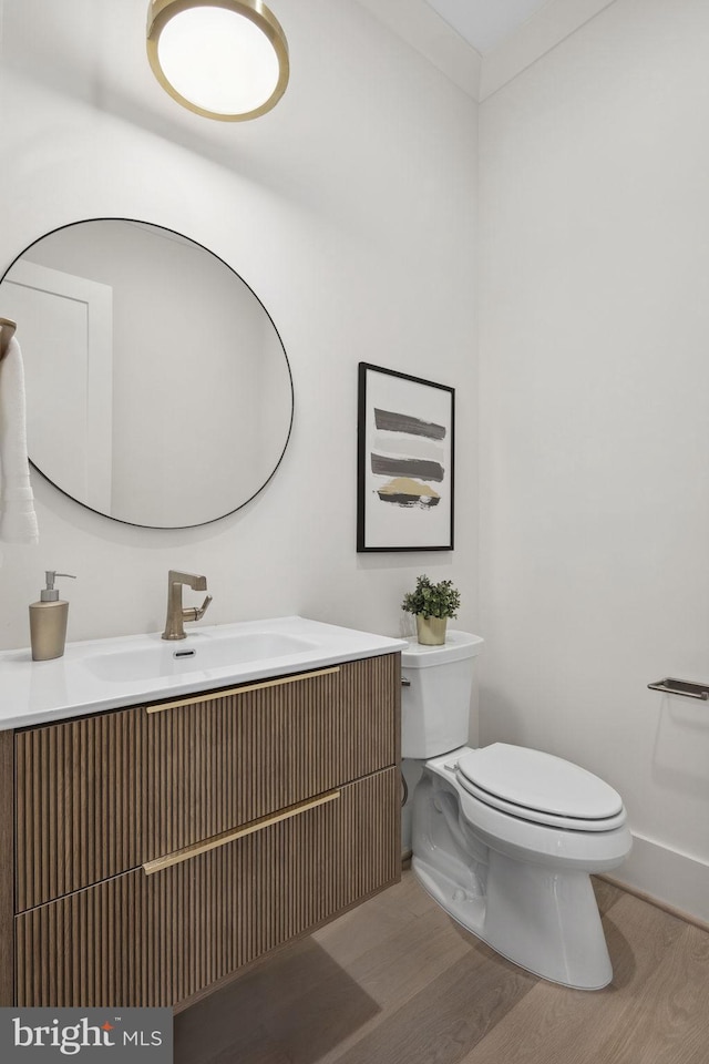 bathroom with toilet, wood finished floors, and vanity