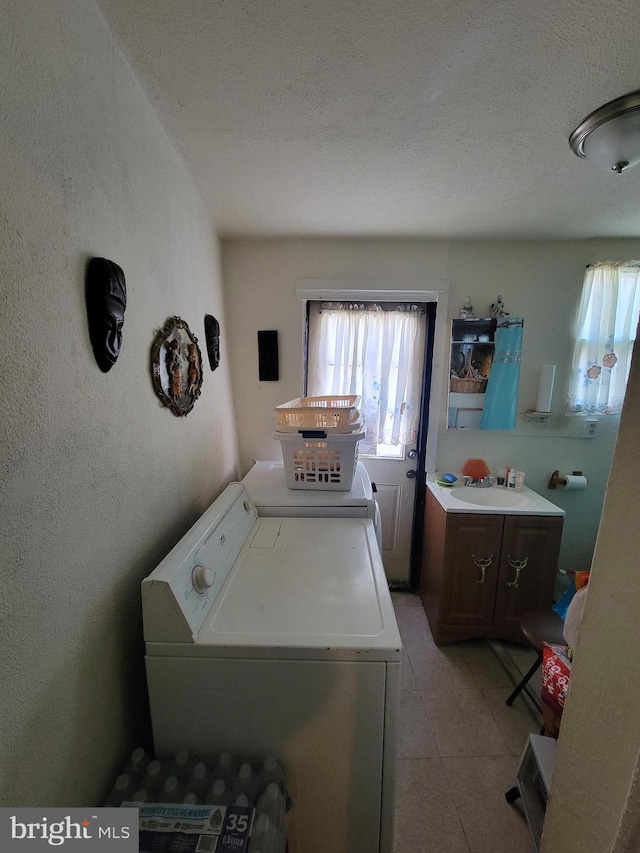 clothes washing area with washer and clothes dryer, a textured ceiling, and sink