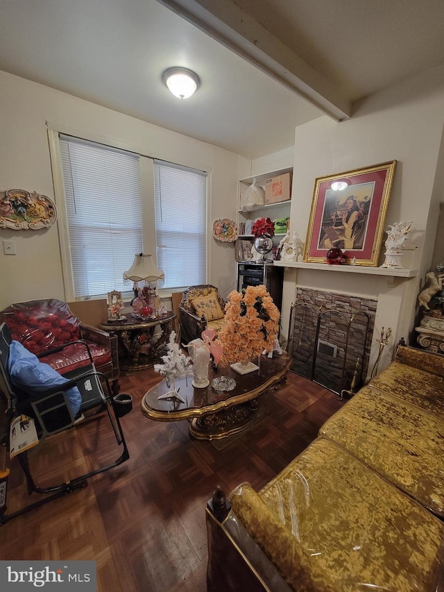 living room with beam ceiling, a stone fireplace, and parquet floors