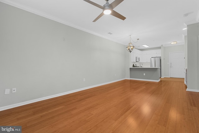 unfurnished living room featuring light hardwood / wood-style flooring, ceiling fan with notable chandelier, and ornamental molding