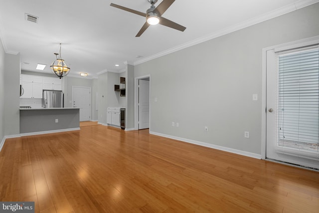 unfurnished living room with crown molding, ceiling fan with notable chandelier, and light wood-type flooring