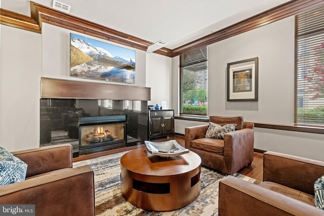 sitting room featuring a fireplace, wood-type flooring, and ornamental molding