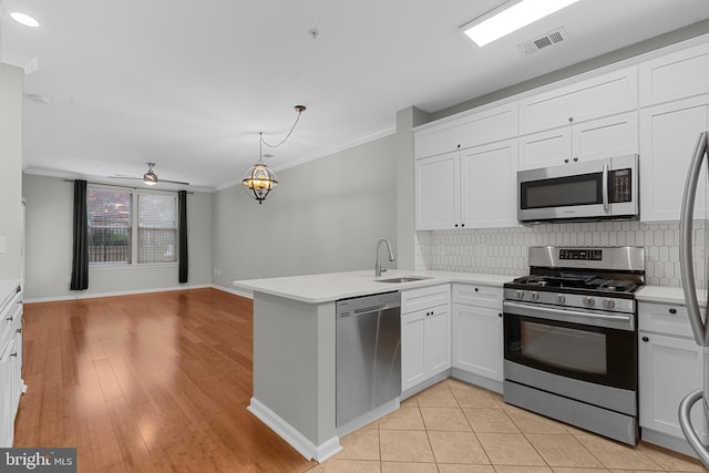 kitchen with kitchen peninsula, ornamental molding, stainless steel appliances, sink, and light hardwood / wood-style floors