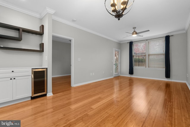 unfurnished living room with ceiling fan with notable chandelier, light wood-type flooring, beverage cooler, and crown molding